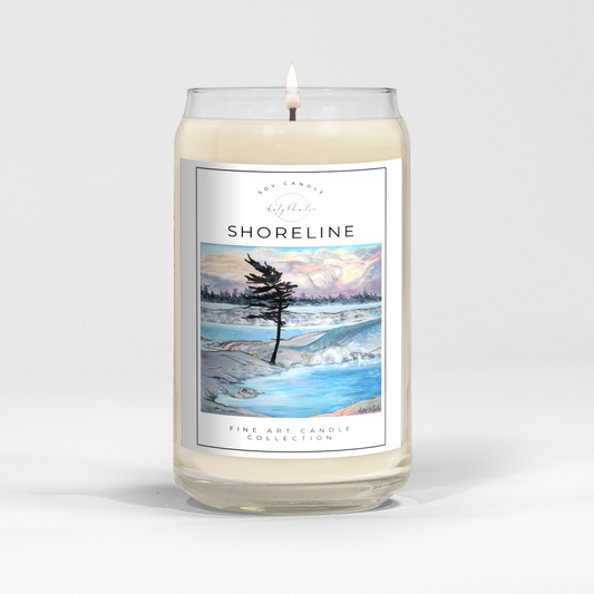 close up of burning white wax candle in a clear glass vessel with fine art landscape painting by Manitoba Artist Katy Martin on label