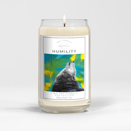 close up of burning white wax candle in a clear glass vessel with fine art wildlife painting of a wolf by Manitoba Artist Katy Martin on label