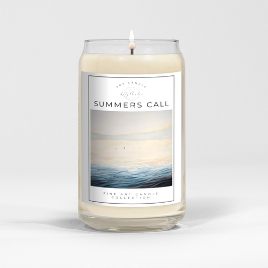 close up of burning white wax candle in a clear glass vessel with fine art landscape painting of loons on a misty lake by Manitoba Artist Katy Martin on label