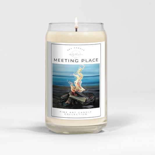 close up of burning white wax candle in a clear glass vessel with fine art landscape painting of a lakeside fire by Manitoba Artist Katy Martin on label