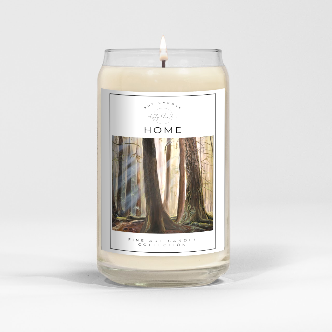 close up of burning white wax candle in a clear glass vessel with fine art landscape painting by Manitoba Artist Katy Martin on label