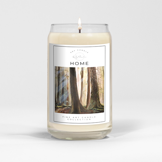 close up of burning white wax candle in a clear glass vessel with fine art landscape painting by Manitoba Artist Katy Martin on label