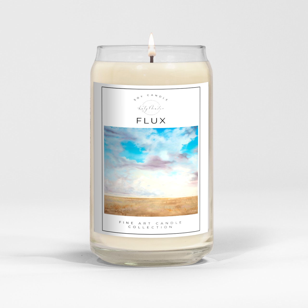 close up of burning white wax candle in a clear glass vessel with fine art landscape painting by Manitoba Artist Katy Martin on label