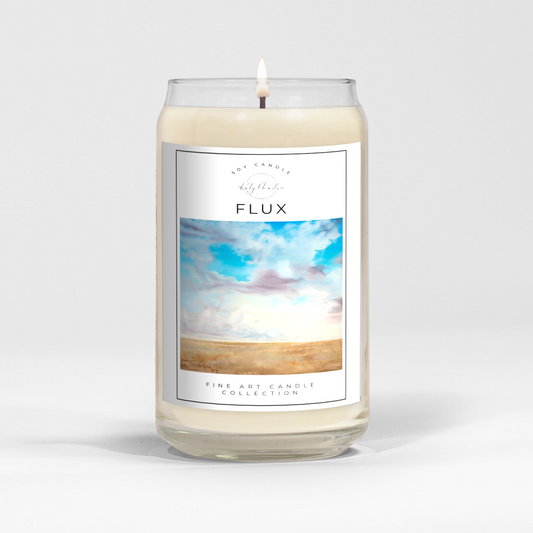 close up of burning white wax candle in a clear glass vessel with fine art landscape painting by Manitoba Artist Katy Martin on label