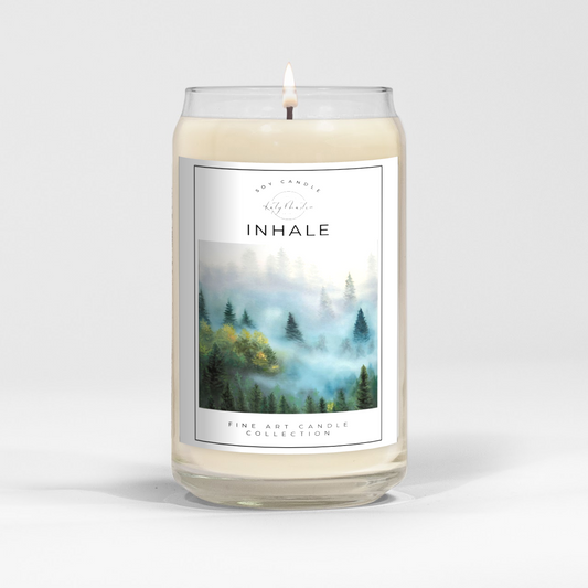 close up of burning white wax candle in a clear glass vessel with fine art landscape painting by Manitoba Artist Katy Martin on label