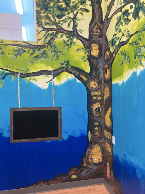 Colorful interior mural of a tree on the walls of the toy store hid'n hollow in Neepawa MB.