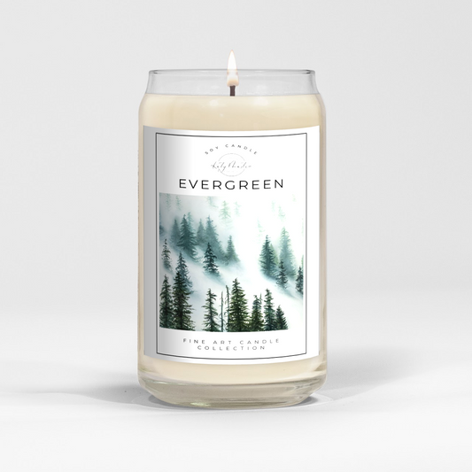 close up of burning white wax candle in a clear glass vessel with fine art landscape painting by Manitoba Artist Katy Martin on label