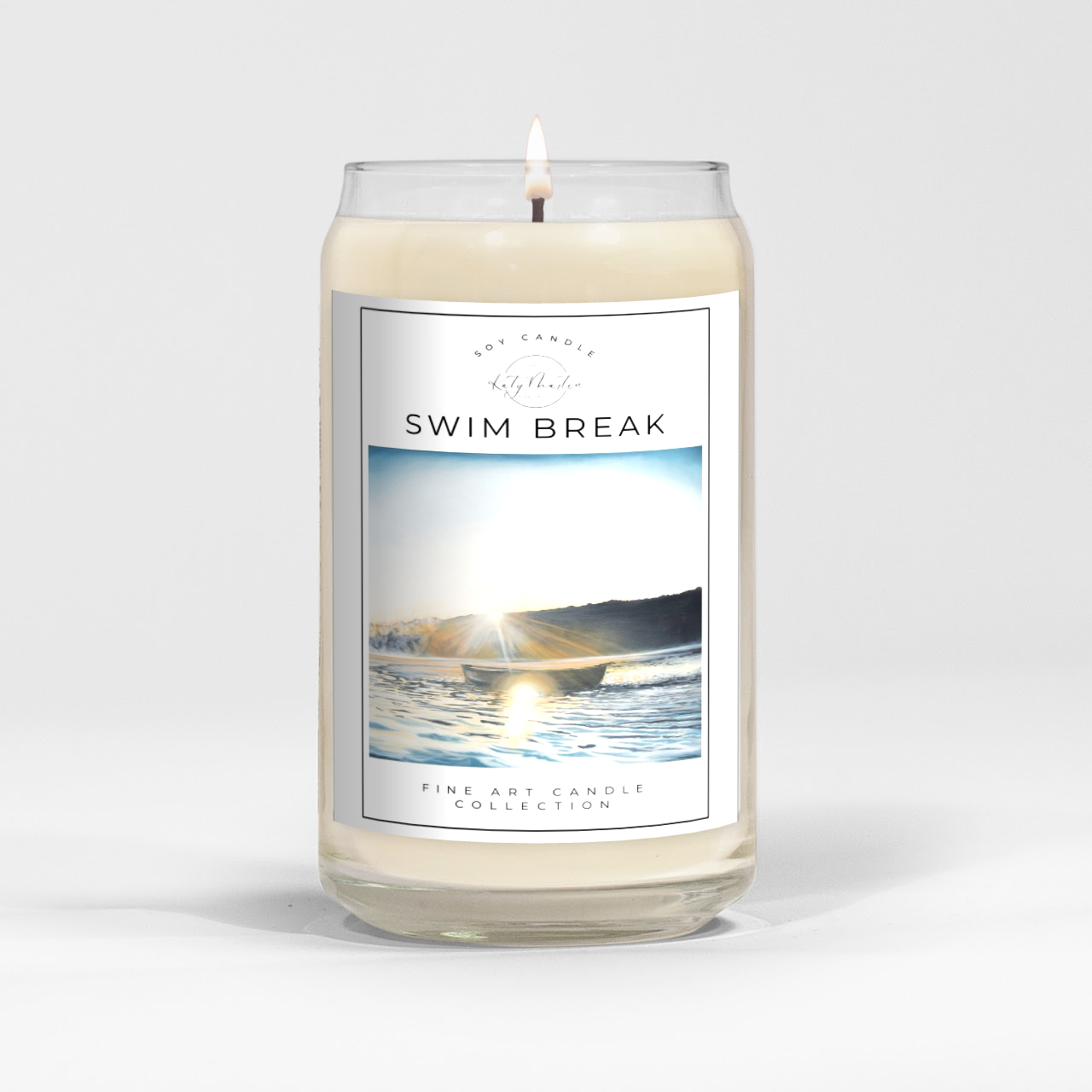 close up of burning white wax candle in a clear glass vessel with fine art landscape painting by Manitoba Artist Katy Martin on label
