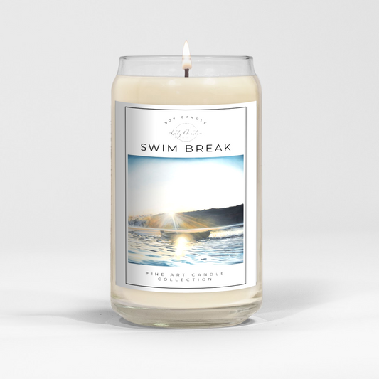 close up of burning white wax candle in a clear glass vessel with fine art landscape painting by Manitoba Artist Katy Martin on label