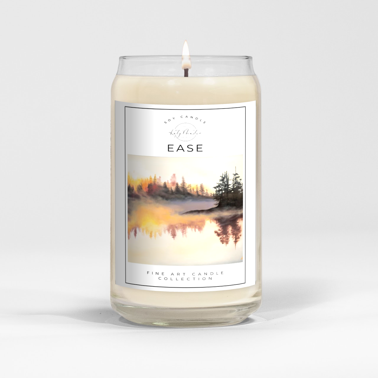 close up of burning white wax candle in a clear glass vessel with fine art landscape painting by Manitoba Artist Katy Martin on label