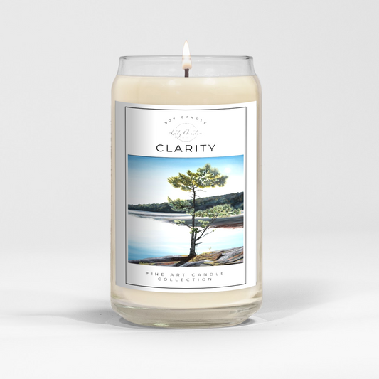 close up of burning white wax candle in a clear glass vessel with fine art landscape painting by Manitoba Artist Katy Martin on label 